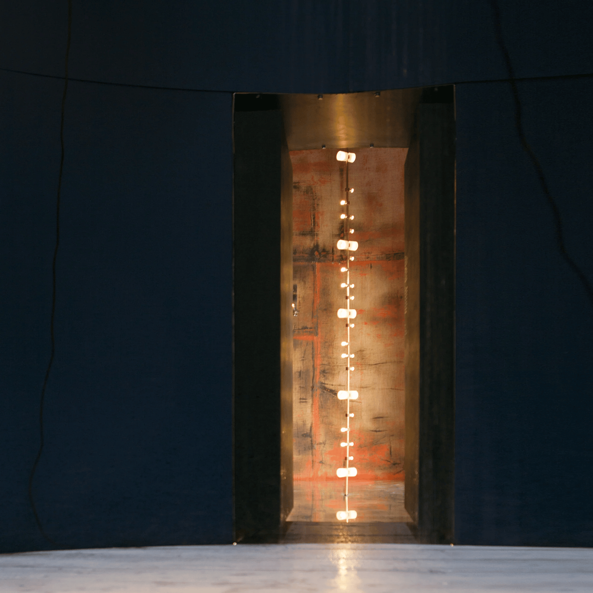 Tall rectangular metal fireplace with glowing interior against a dark background