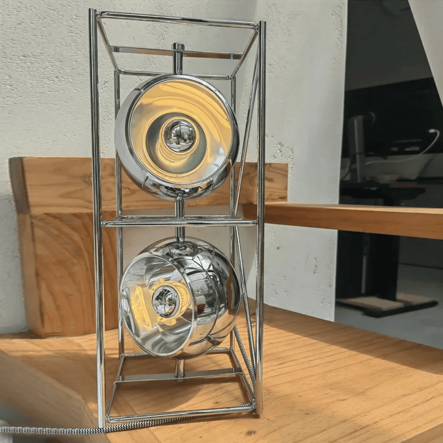 Modern silver lamp with two circular designs on a wooden surface.