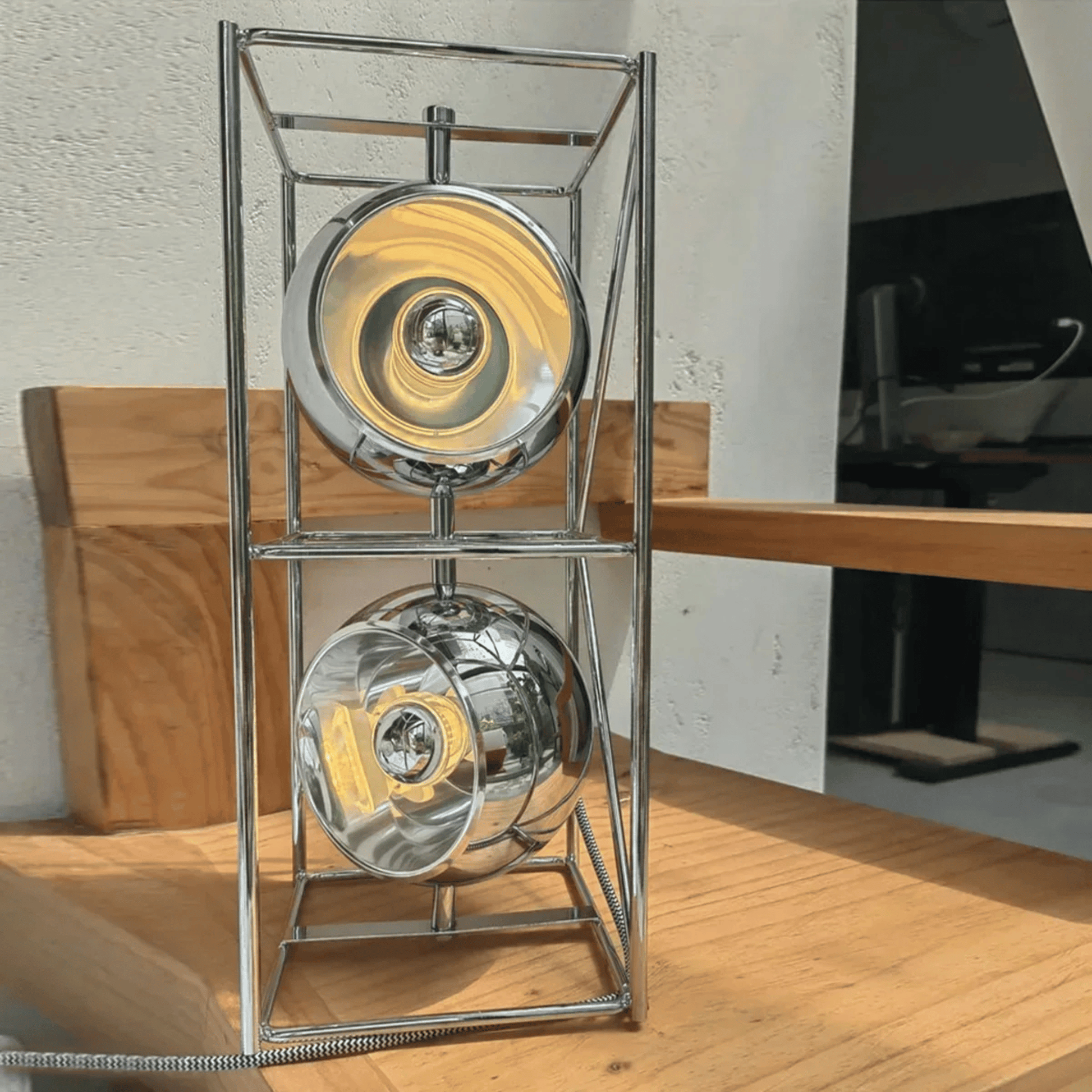 Modern silver lamp with two circular designs on a wooden surface.