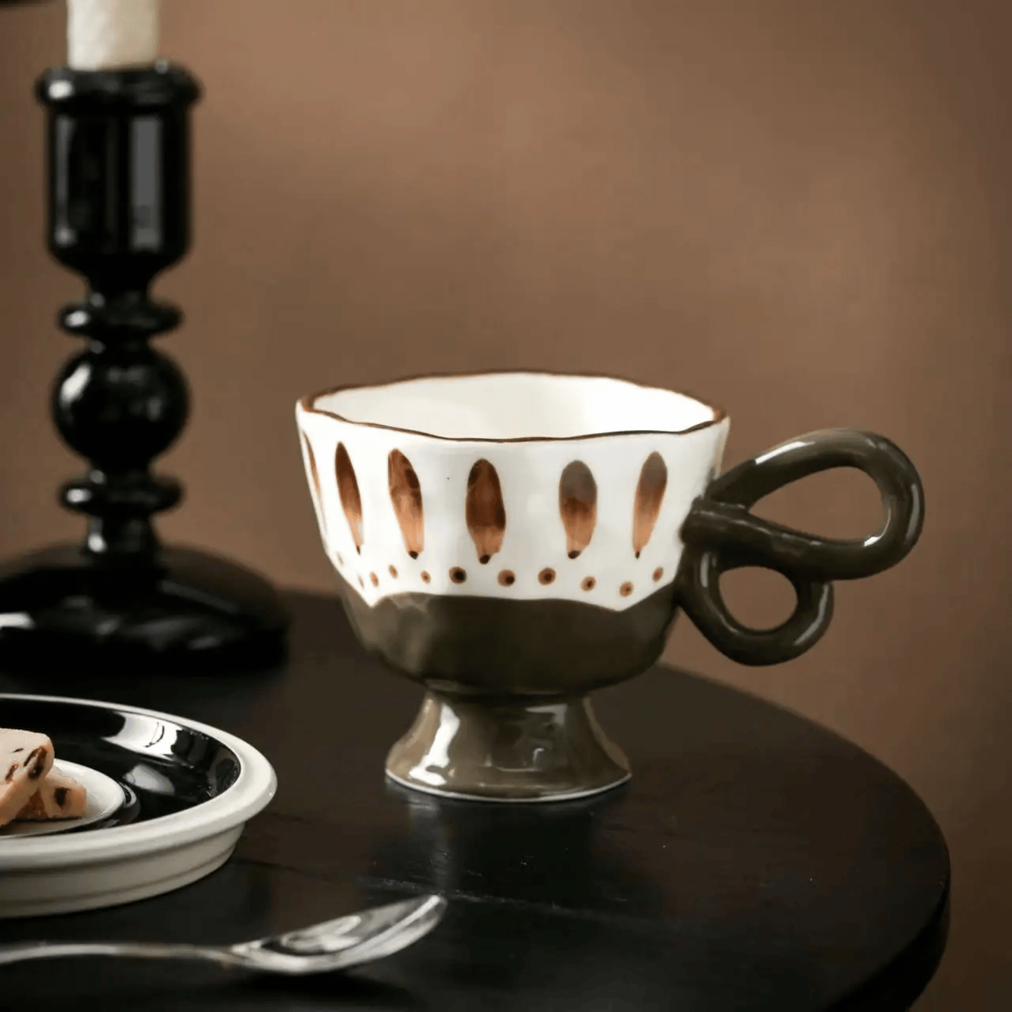 Decorative cup with a unique handle design on a dark surface.