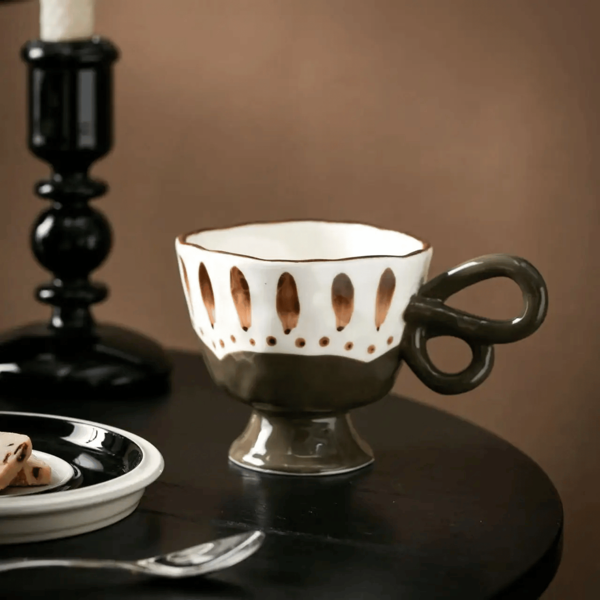 Decorative cup with a unique handle design on a dark surface.