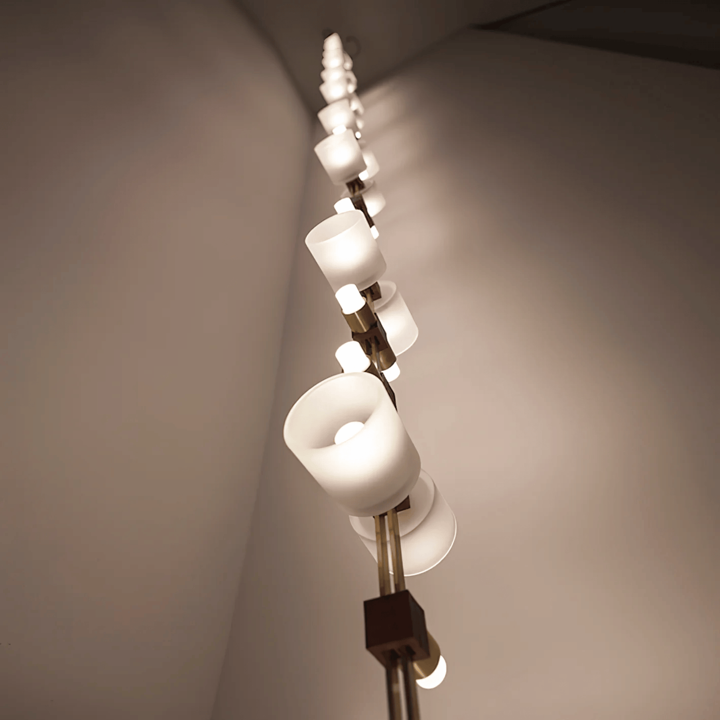 Modern chandelier with white lampshades against a neutral wall