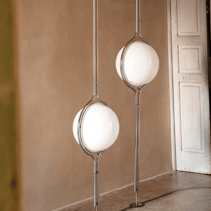 Modern floor lamps with spherical glass shades in a room with beige walls and a white door.