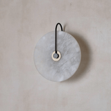 Round marble wall hook with black strap on a beige background