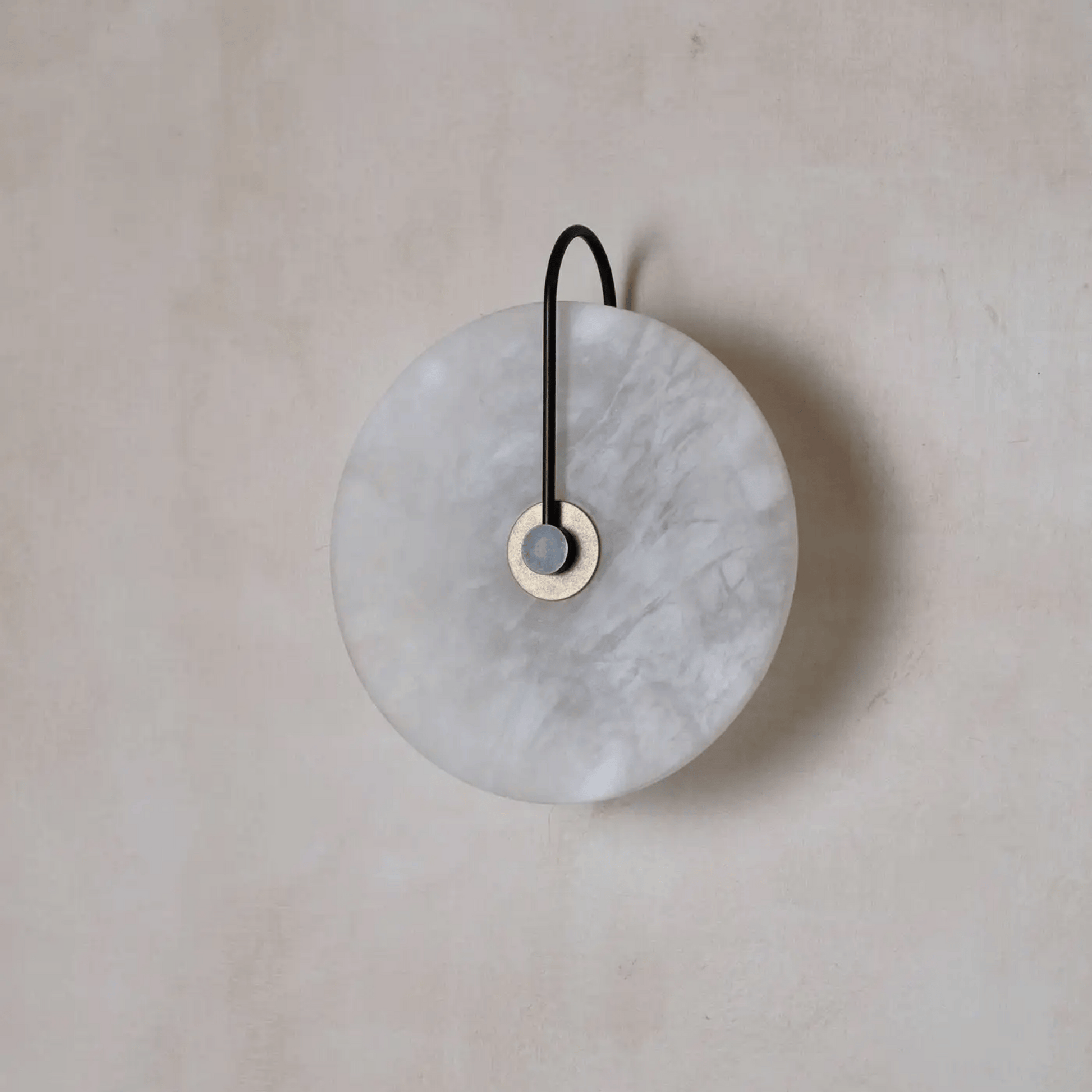 Round marble wall hook with black strap on a beige background