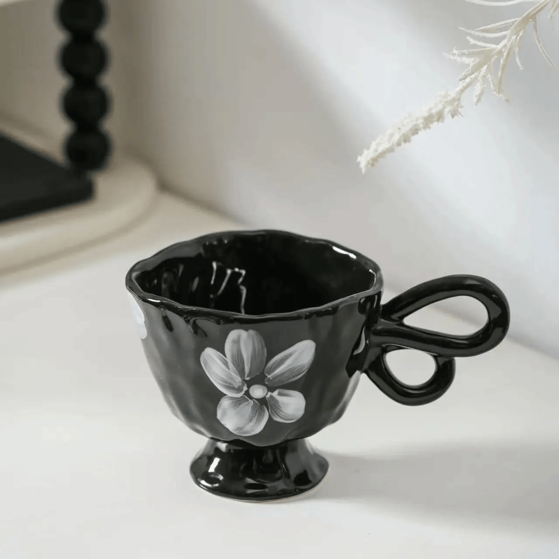 Black ceramic cup with floral design on a white surface
