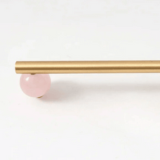 Gold curtain rod with a pink ball finial on a white background