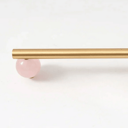 Gold curtain rod with a pink ball finial on a white background