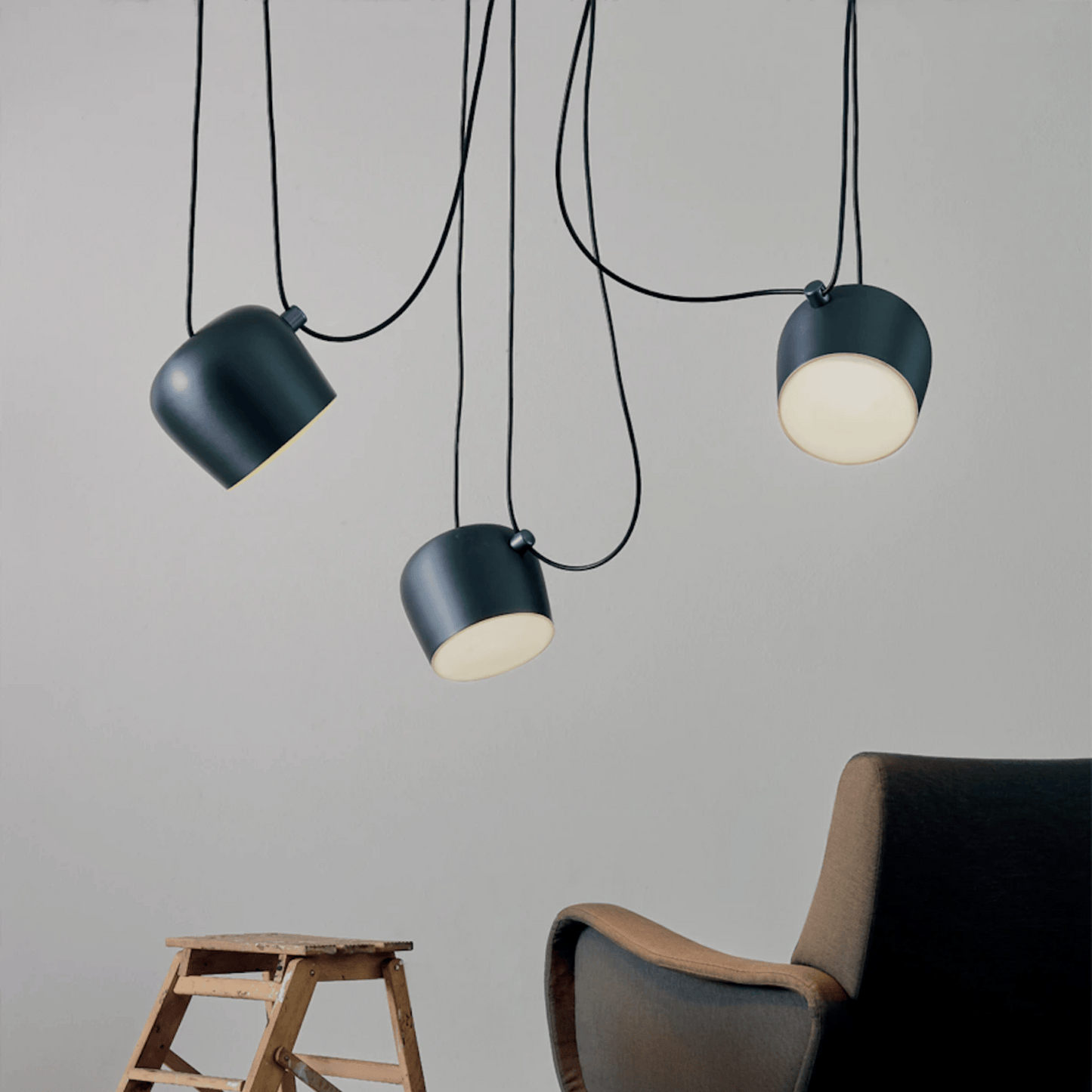 Three pendant lights hanging from the ceiling with a chair and stool in the foreground.