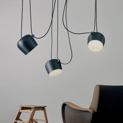 Three pendant lights hanging from the ceiling with a chair and stool in the foreground.