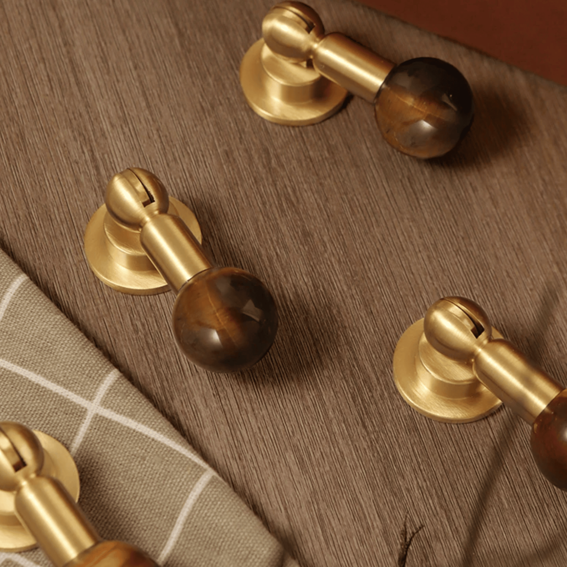 Close-up of wooden cabinet knobs with gold metal accents on a wooden surface.
