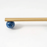 Gold rod with a blue spherical object on a white background