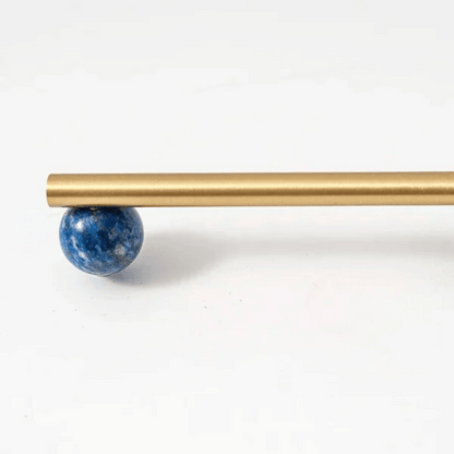 Gold rod with a blue spherical object on a white background