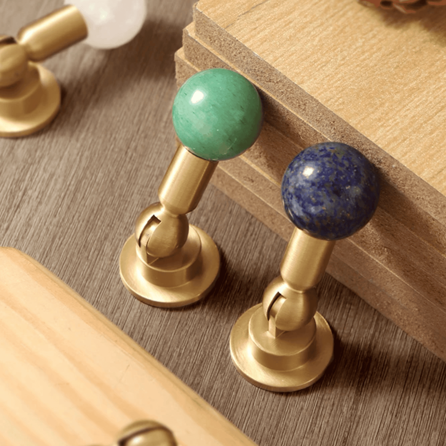 Decorative drawer handles with gold finish and gemstone knobs on a wooden surface.