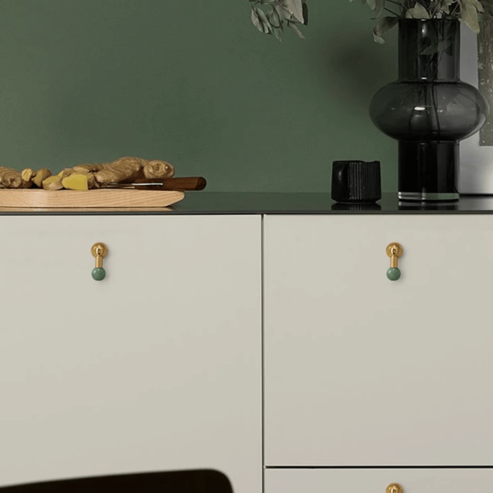 Cabinets with gold and green knobs on a green wall background