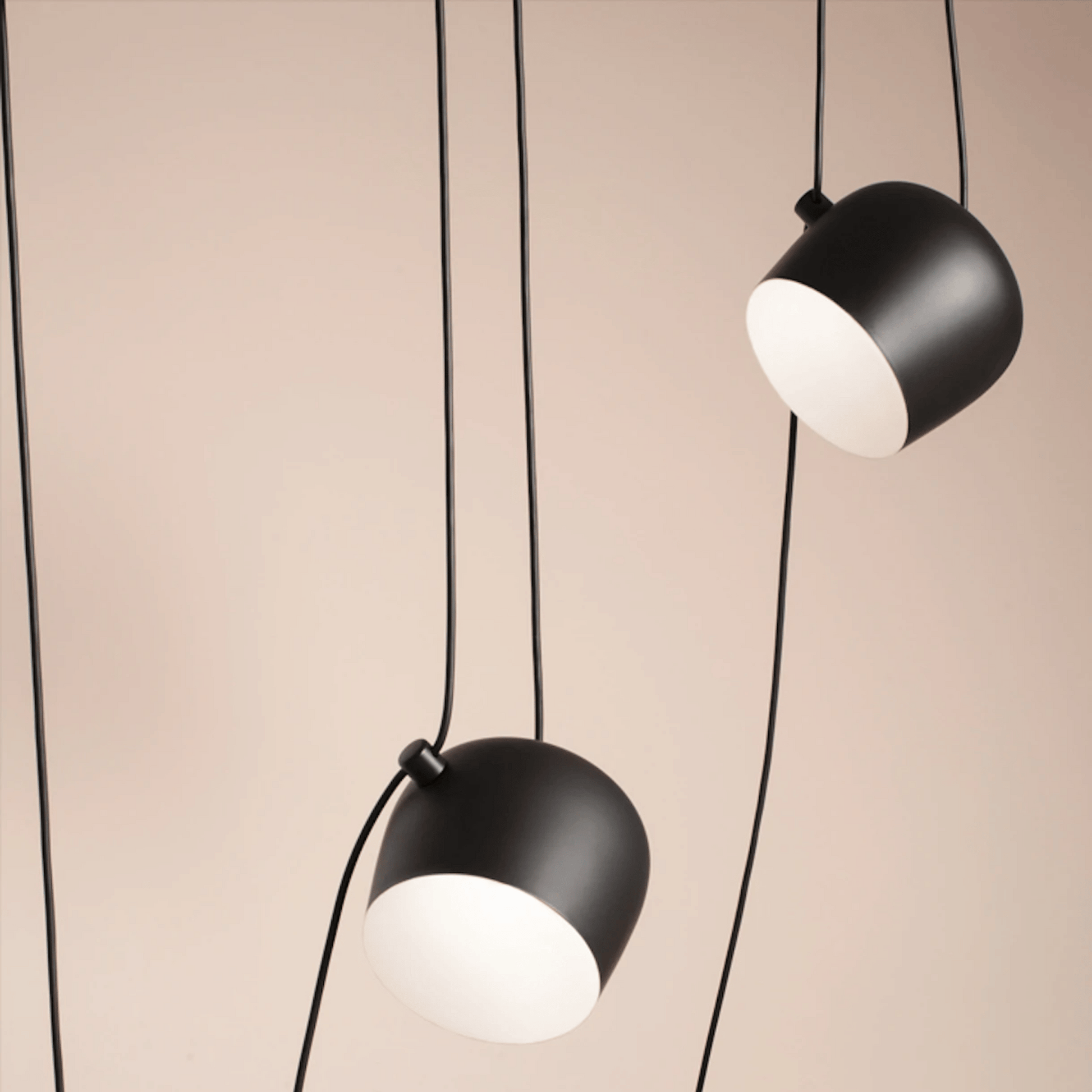 Two black pendant lights with white bulbs on a beige background