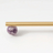 Gold rod with a purple amethyst crystal on a white background
