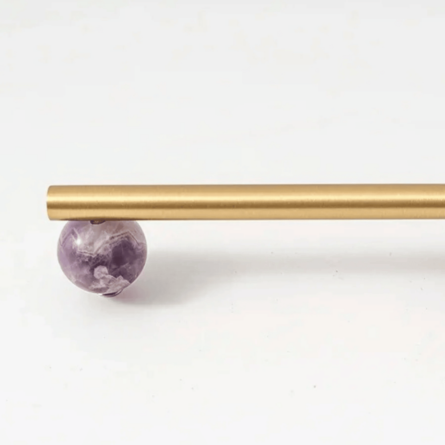 Gold rod with a purple amethyst crystal on a white background