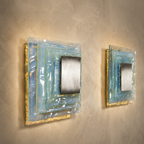Two wall-mounted square mirrors with decorative frames on a textured wall.