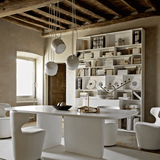Modern dining room with a white table and chairs, bookshelf, and pendant lights.