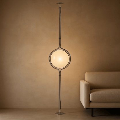 Modern floor lamp with a round glass shade in a room with a beige sofa.