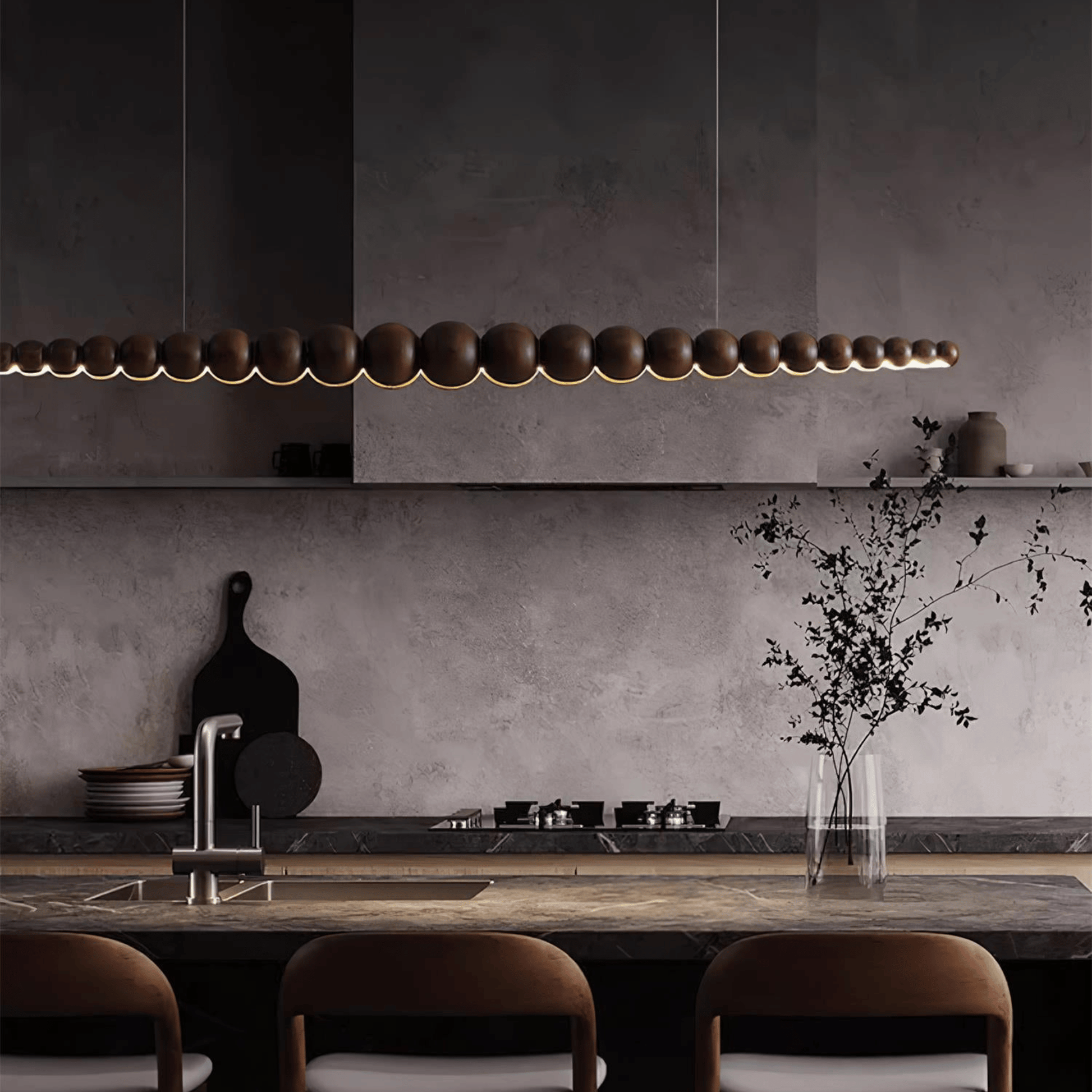 Modern kitchen with a long pendant light fixture, concrete wall, and wooden dining table.