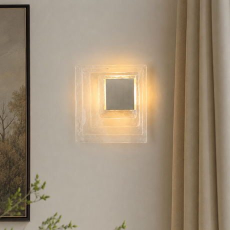 Square wall light fixture on a neutral wall with a painting and plant in the background