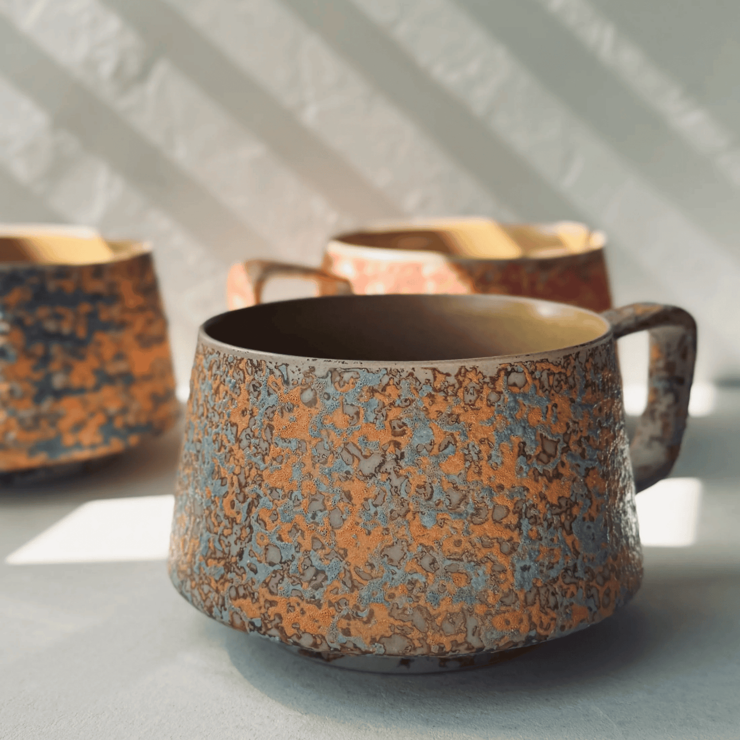 Three ceramic cups with textured surfaces on a light background