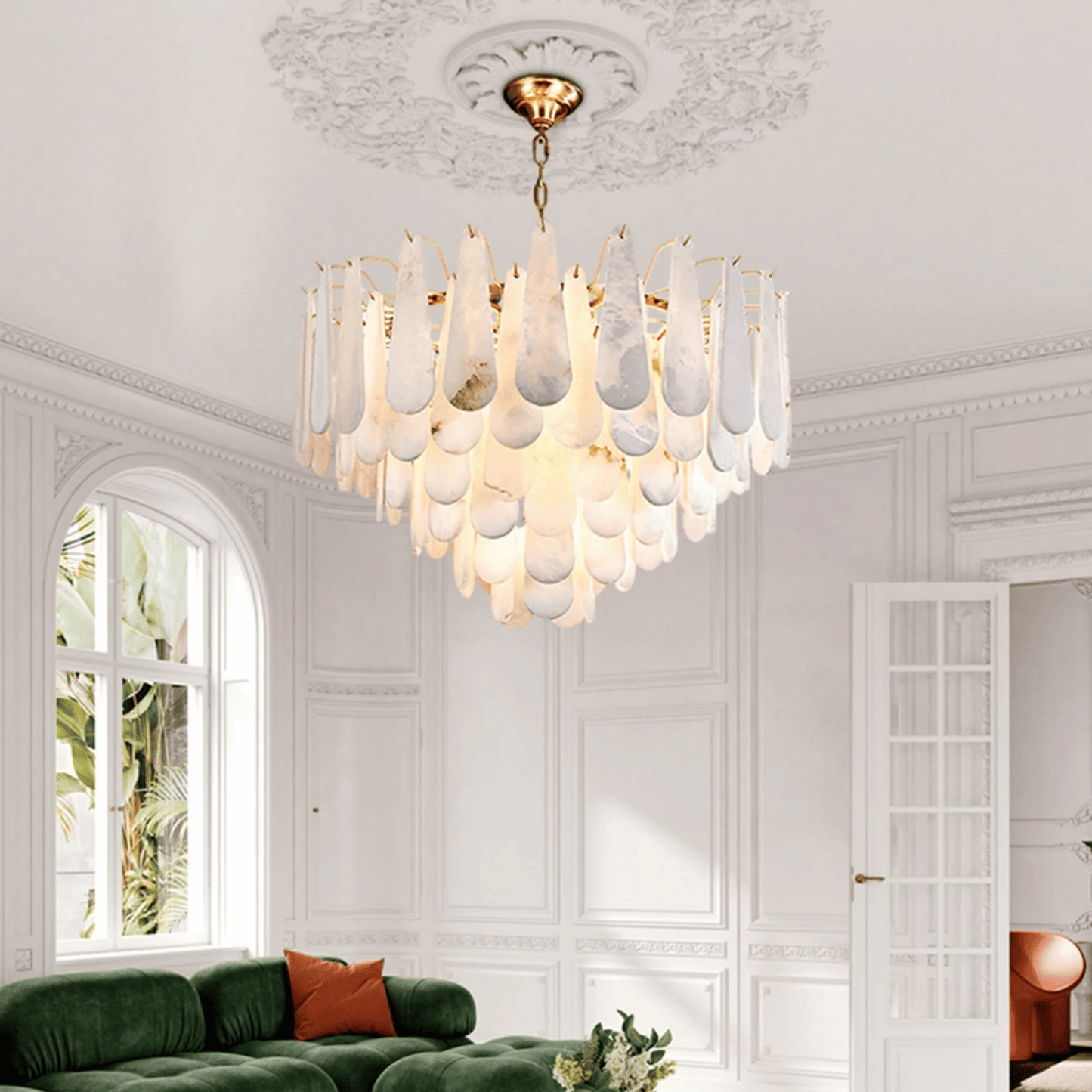 Luxurious chandelier hanging in a stylish living room with white walls and green sofa.