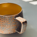 Ceramic mug with a textured handle and interior on a neutral background