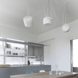Modern kitchen with pendant lights and a dining table.