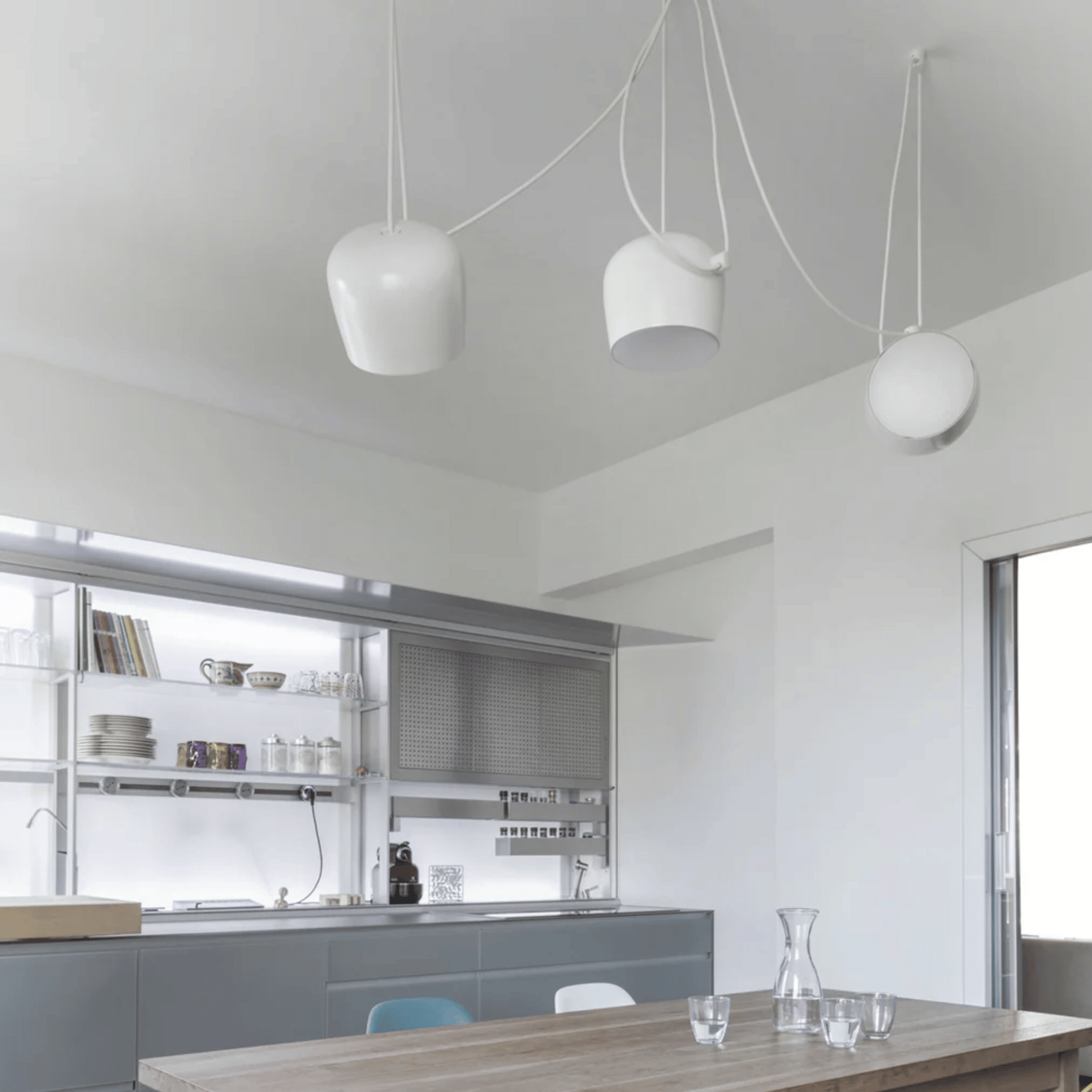 Modern kitchen with pendant lights and a dining table.