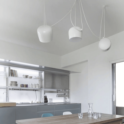 Modern kitchen with pendant lights and a dining table.