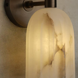 Wall-mounted light fixture with a textured glass shade on a neutral wall.