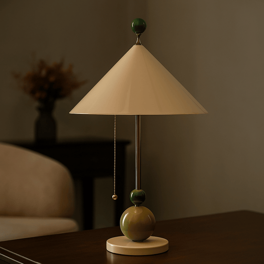 Table lamp with a beige shade and green accents on a wooden surface.