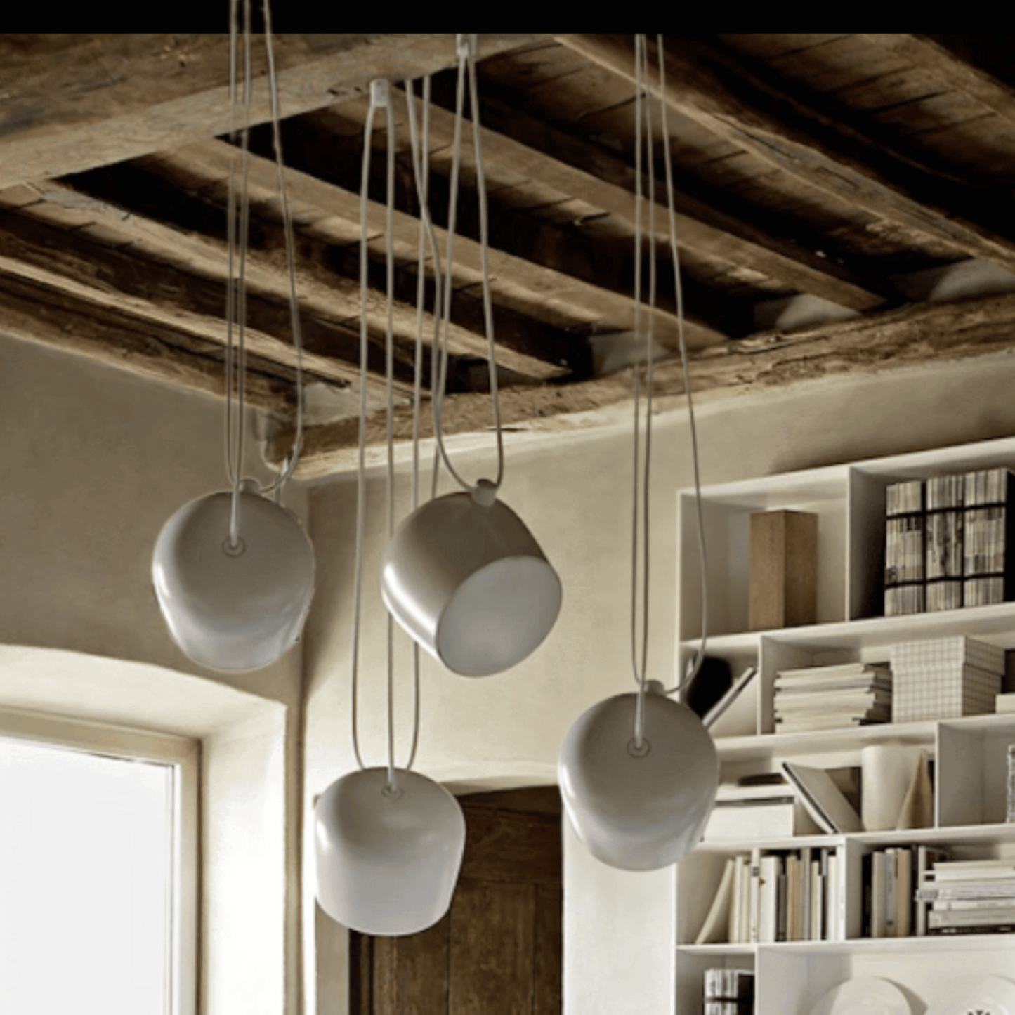 White pendant lights hanging from a wooden ceiling in a modern interior setting.