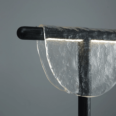 Close-up of a clear glass object with a black handle on a gray background