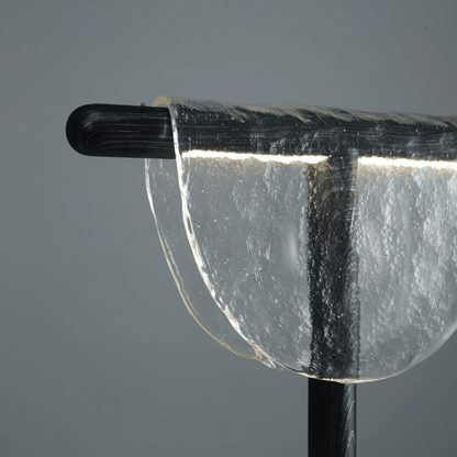 Close-up of a clear glass object with a black handle on a gray background