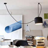 Modern black pendant light hanging in a room with books and artwork on the wall.