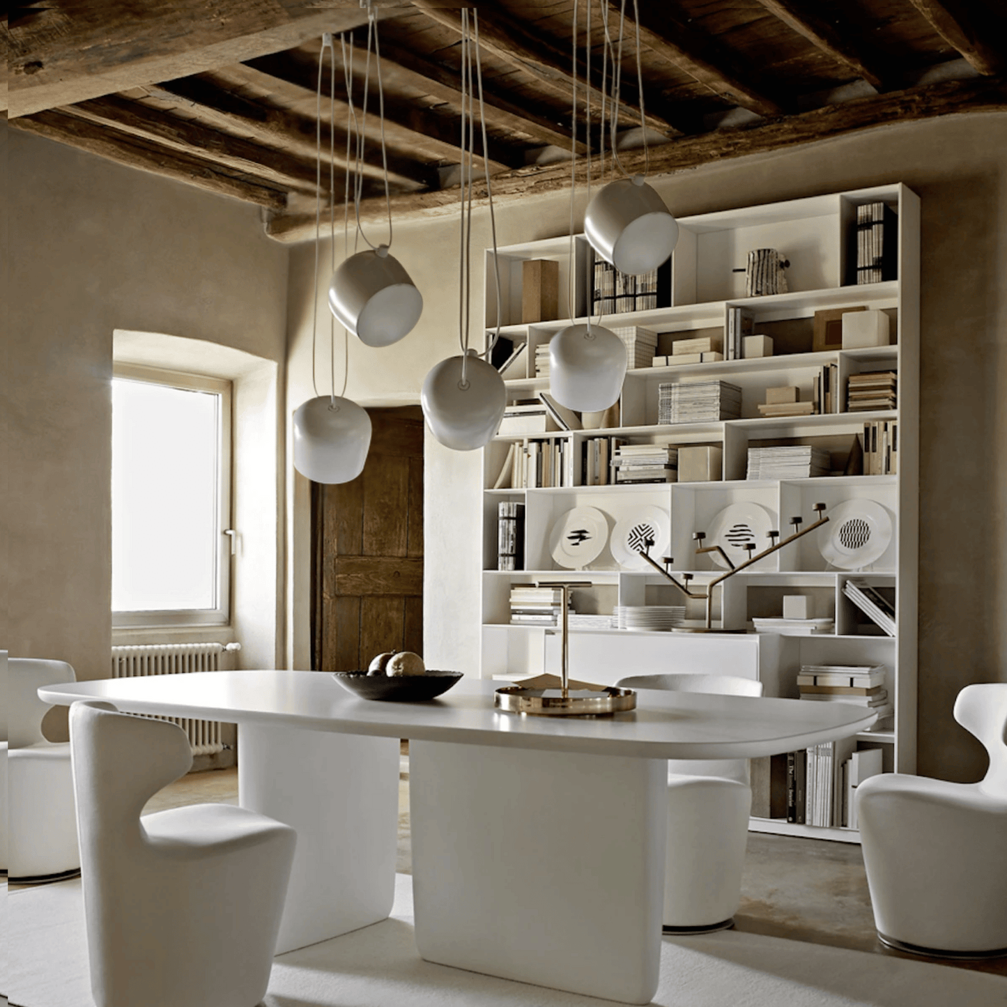 Modern dining room with a white table, chairs, and a bookshelf.