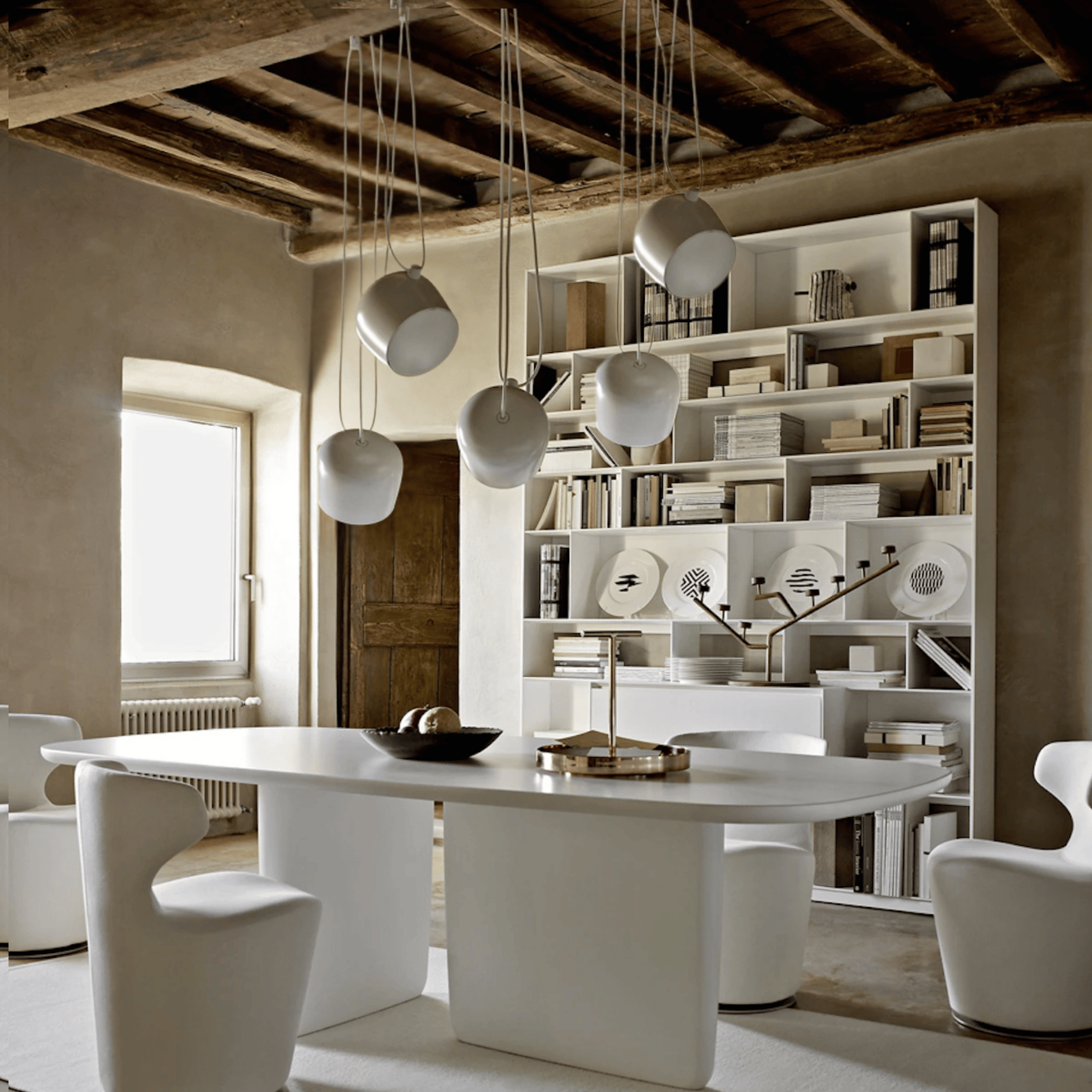 Modern dining room with a white table, chairs, and a bookshelf.