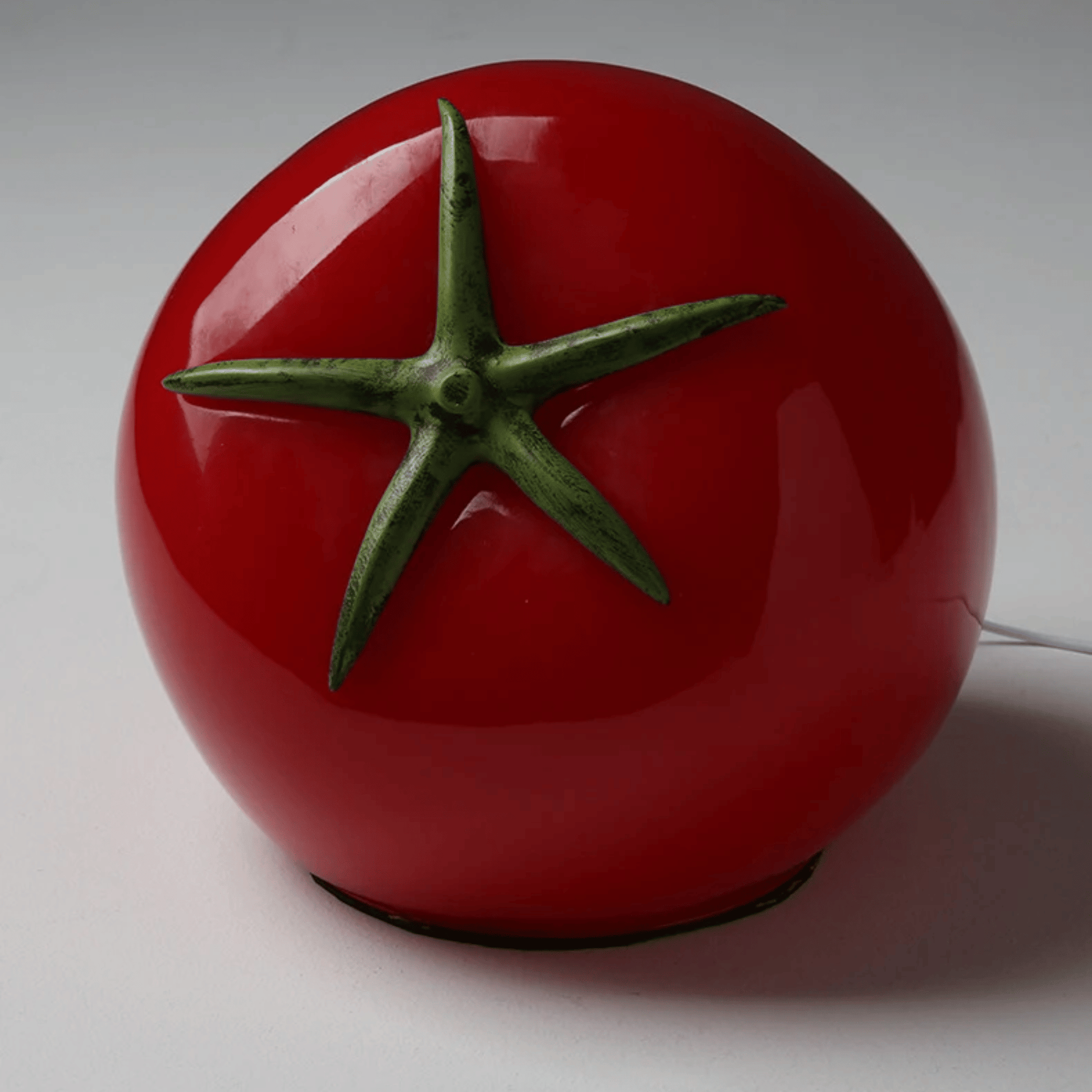 Red tomato-shaped lamp with green stem on a white background