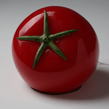 Red tomato-shaped lamp with green stem on a white background