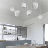 Modern kitchen with white pendant lights and a wooden dining table.