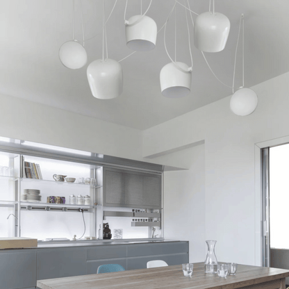 Modern kitchen with white pendant lights and a wooden dining table.