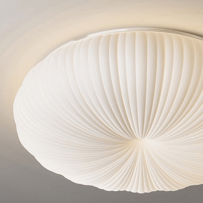 Ceiling light fixture with a white, fan-like design on a neutral background