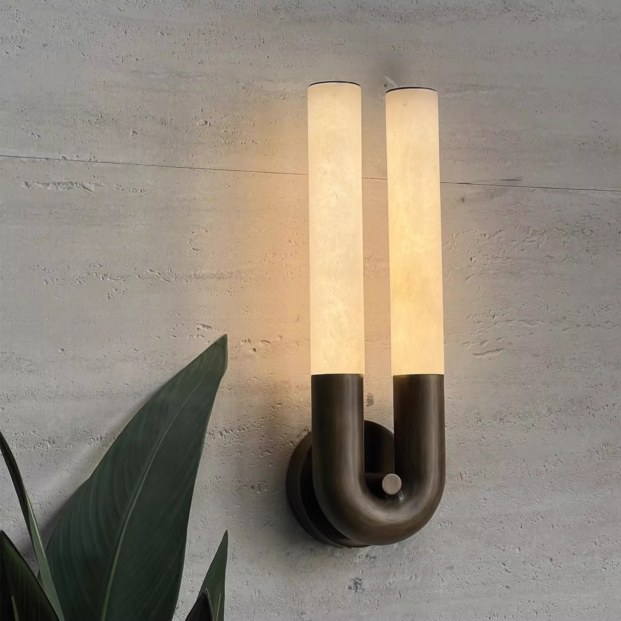Modern wall-mounted light fixture with a plant in the background