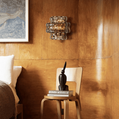 Decorative wall light fixture on a wooden wall with a chair and books below.