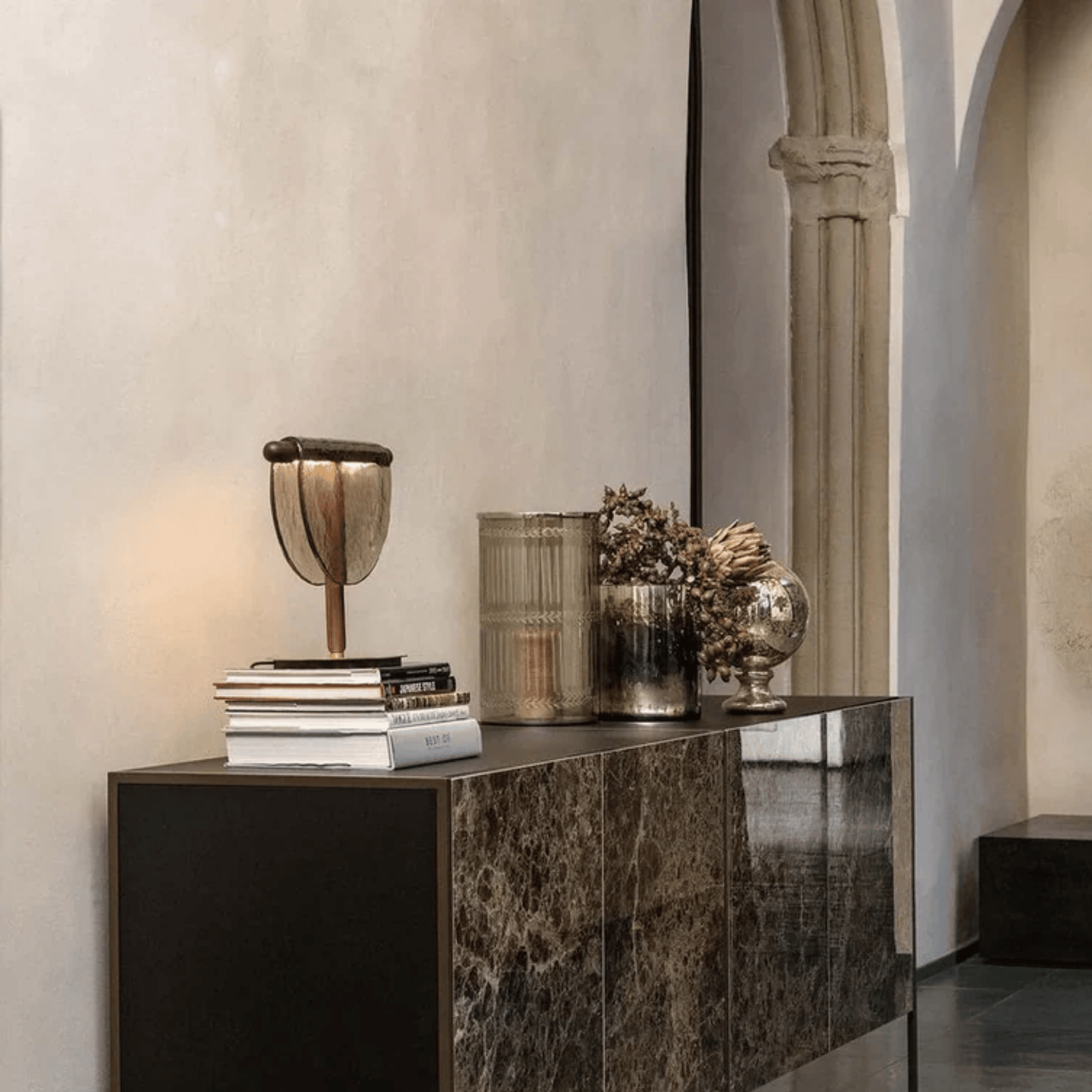 Decorative console table with books, lamp, and decorative items against a neutral wall.