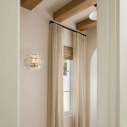 Beige curtains with a wall sconce in a room with wooden beams.